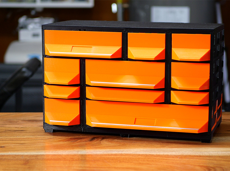 A finished Tabletop Kit standing on a wooden desk: black cases and covers with orange drawers, on its own feet.