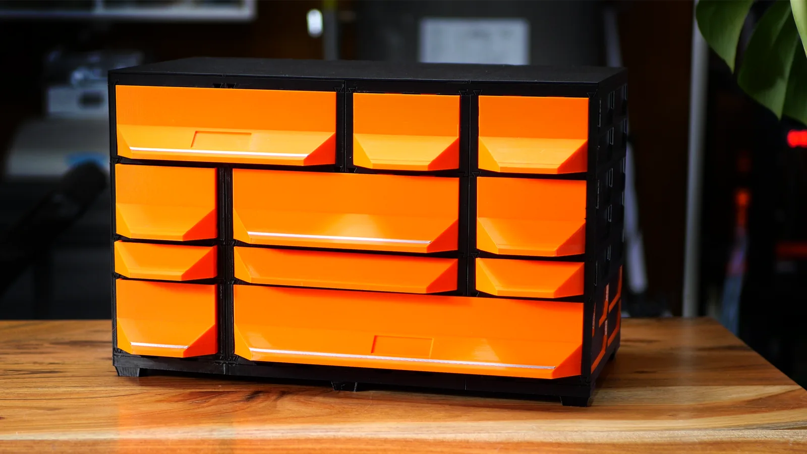 A freestanding MODULITH tabletop build: nine orange drawers of four sizes in black cases on a wooden desk.