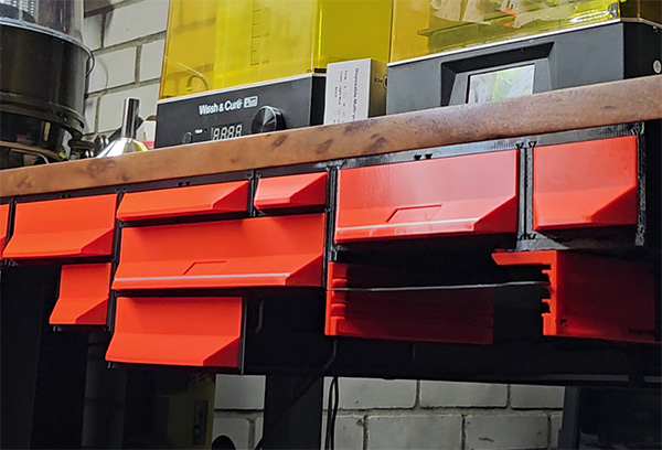 Red drawers hanging under a workbench top on under-table rails