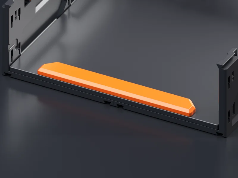 An orange Shelf Lip seated along the front edge of a black Shelf Insert, seen from above with the cover off