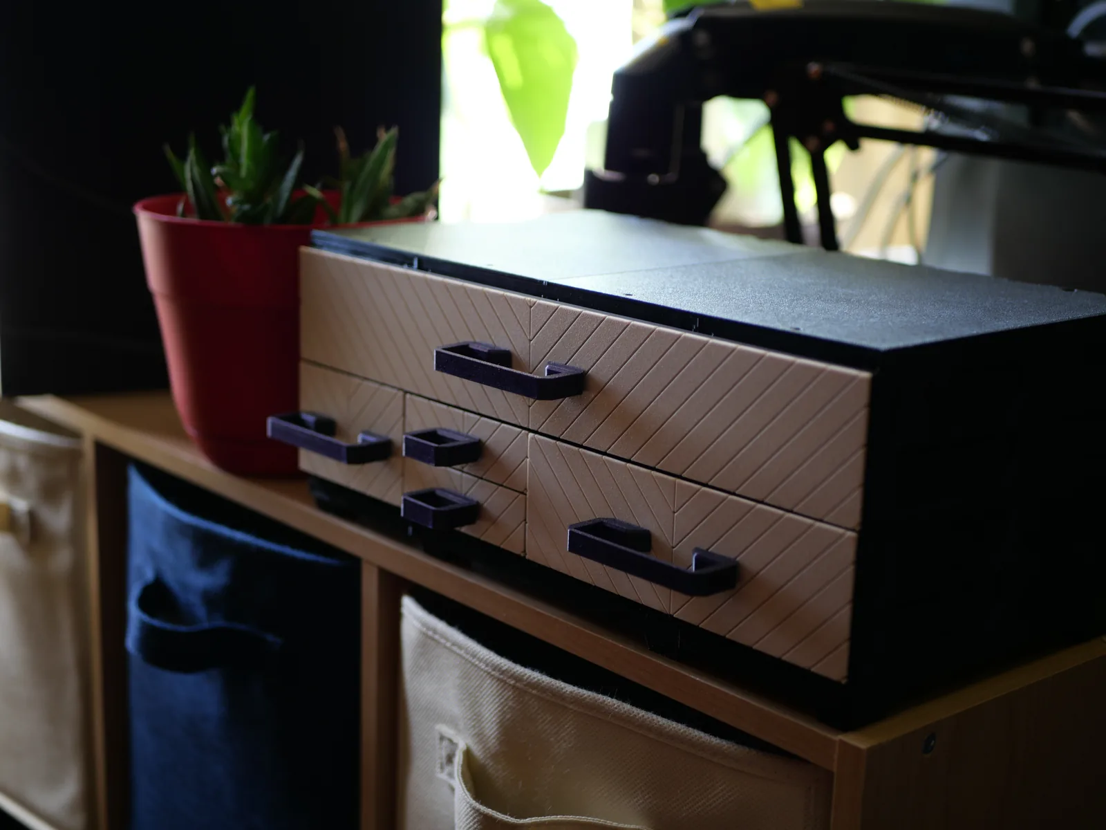 A wide tabletop build with tan Chevron faceplates and dark handles, on a shelf unit by a window