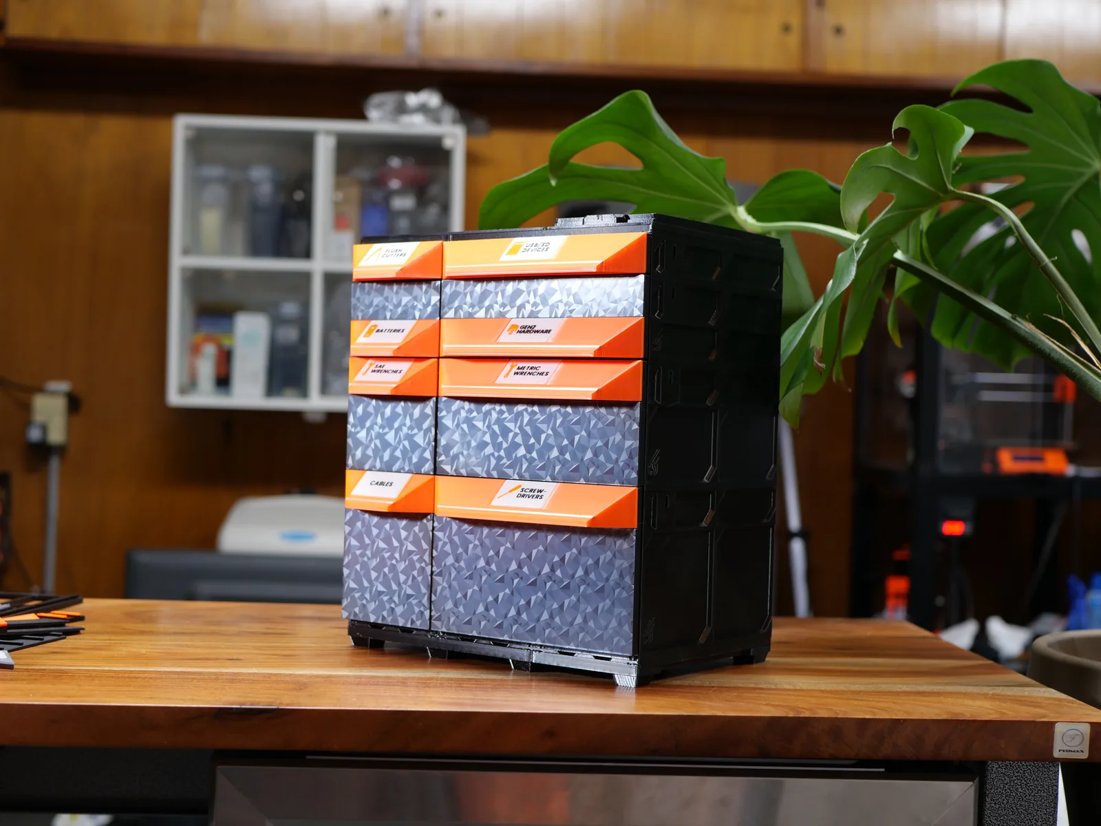A tall tabletop tower of drawers with Classic Pro faceplates: orange grips carrying labels over patterned accent panels, beside a plant