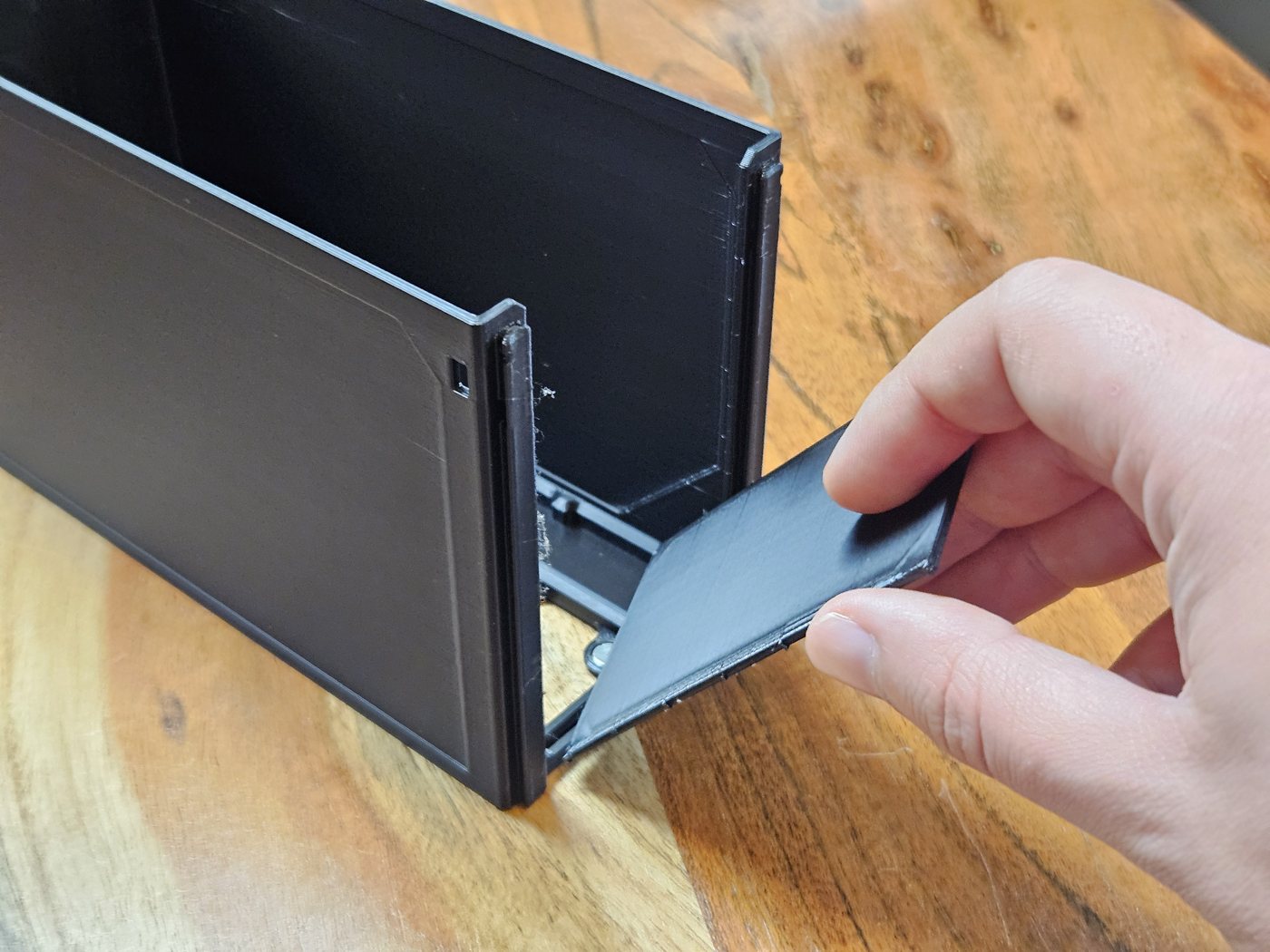 A hand pulling the thin tear-away front out of the end of the drawer
